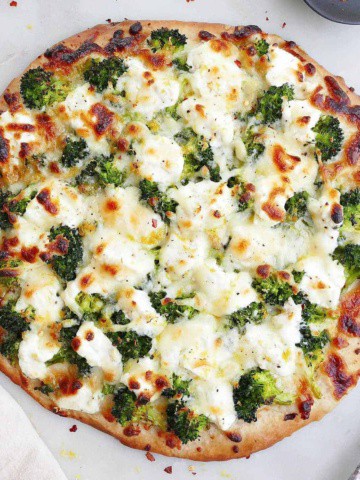 square image of white pizza with broccoli on a counter