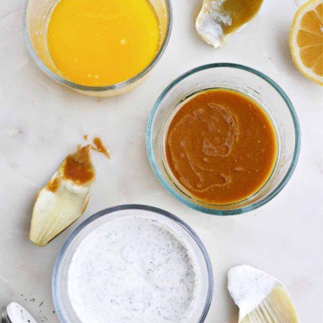 three artichoke dipping sauces in glass containers next to each other