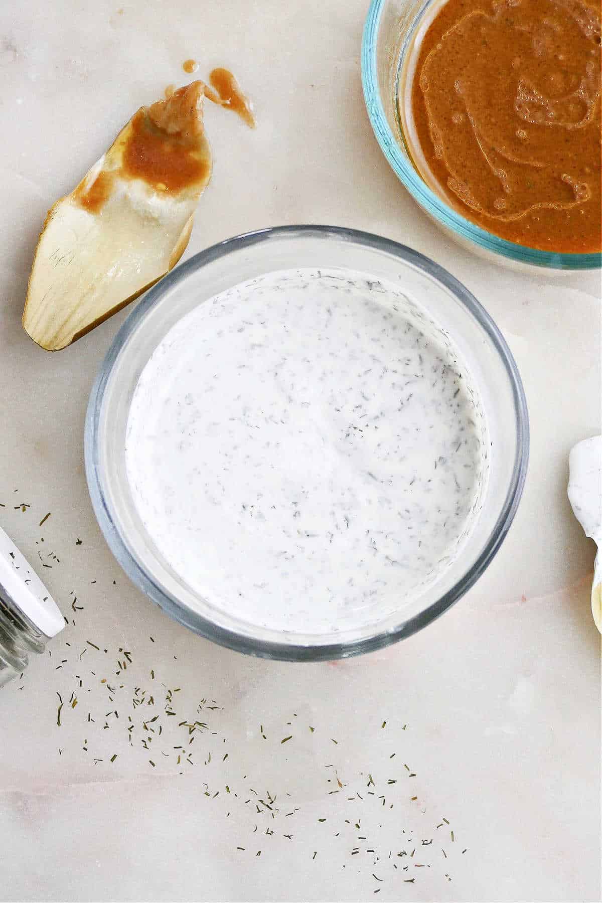 dill yogurt artichoke dipping sauce in a glass container on a counter