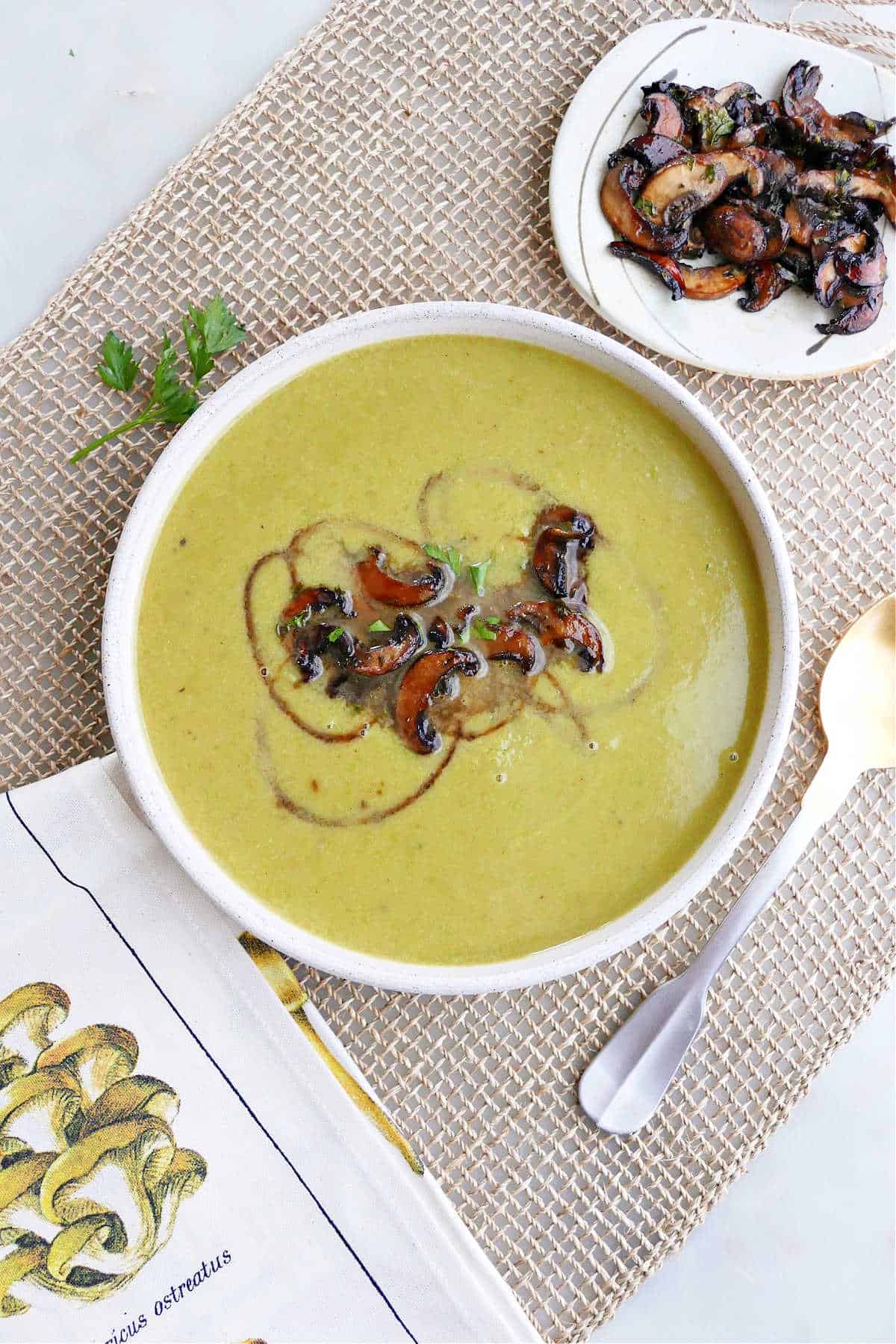 asparagus soup topped with balsamic mushrooms on a placemat on a counter