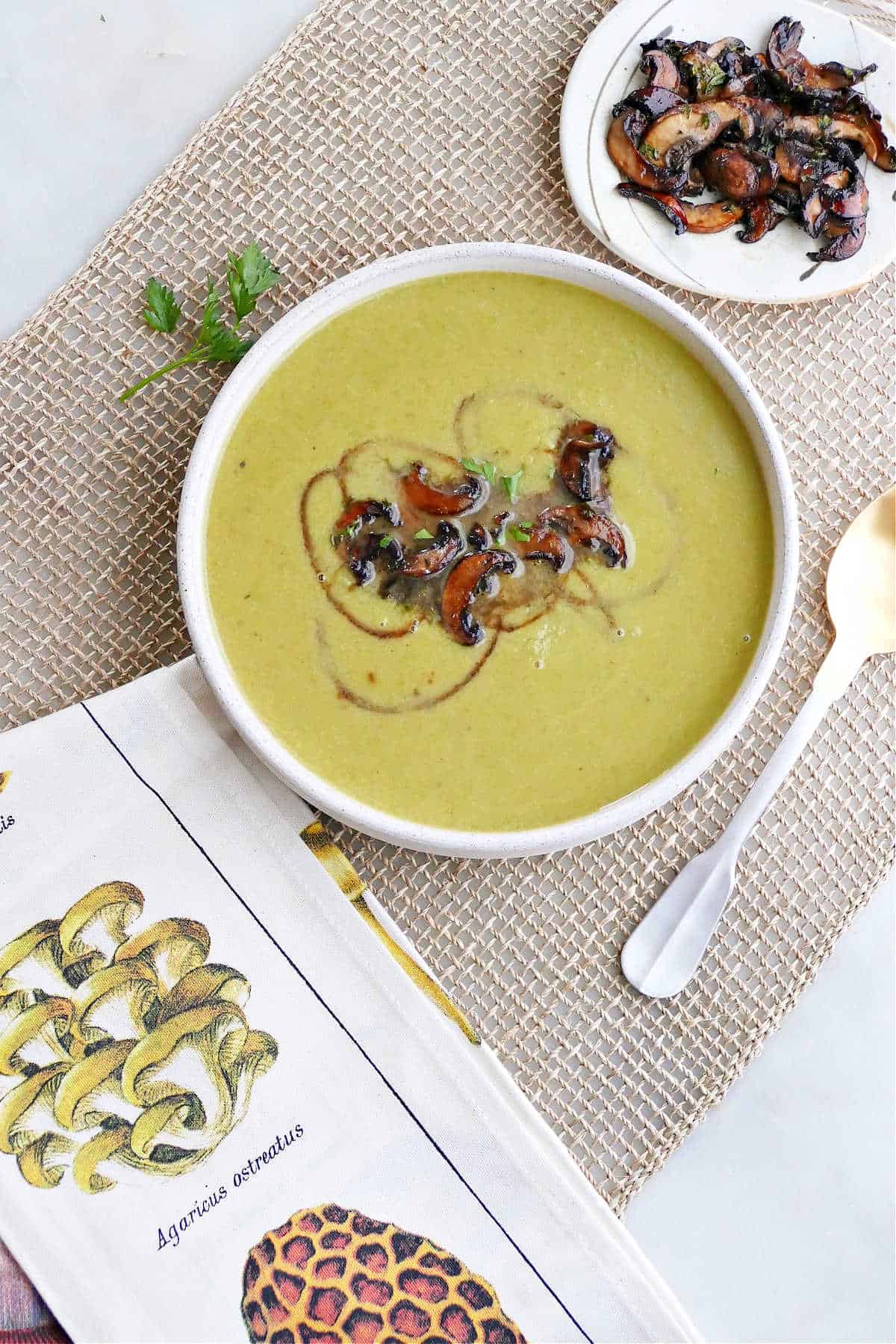 asparagus soup topped with balsamic mushrooms on a placemat on a counter