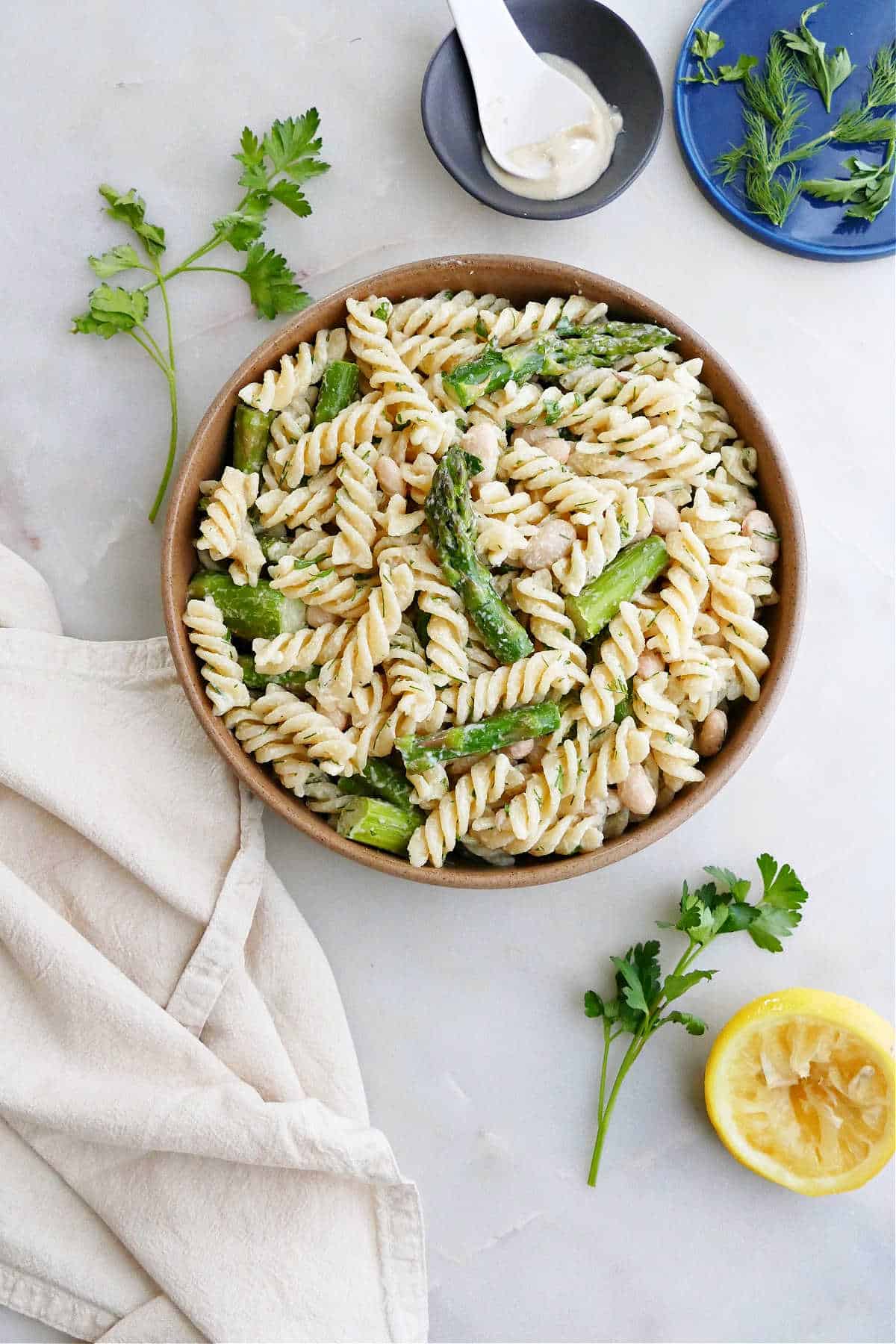 asparagus pasta salad on a serving plate next to ingredients on a counter