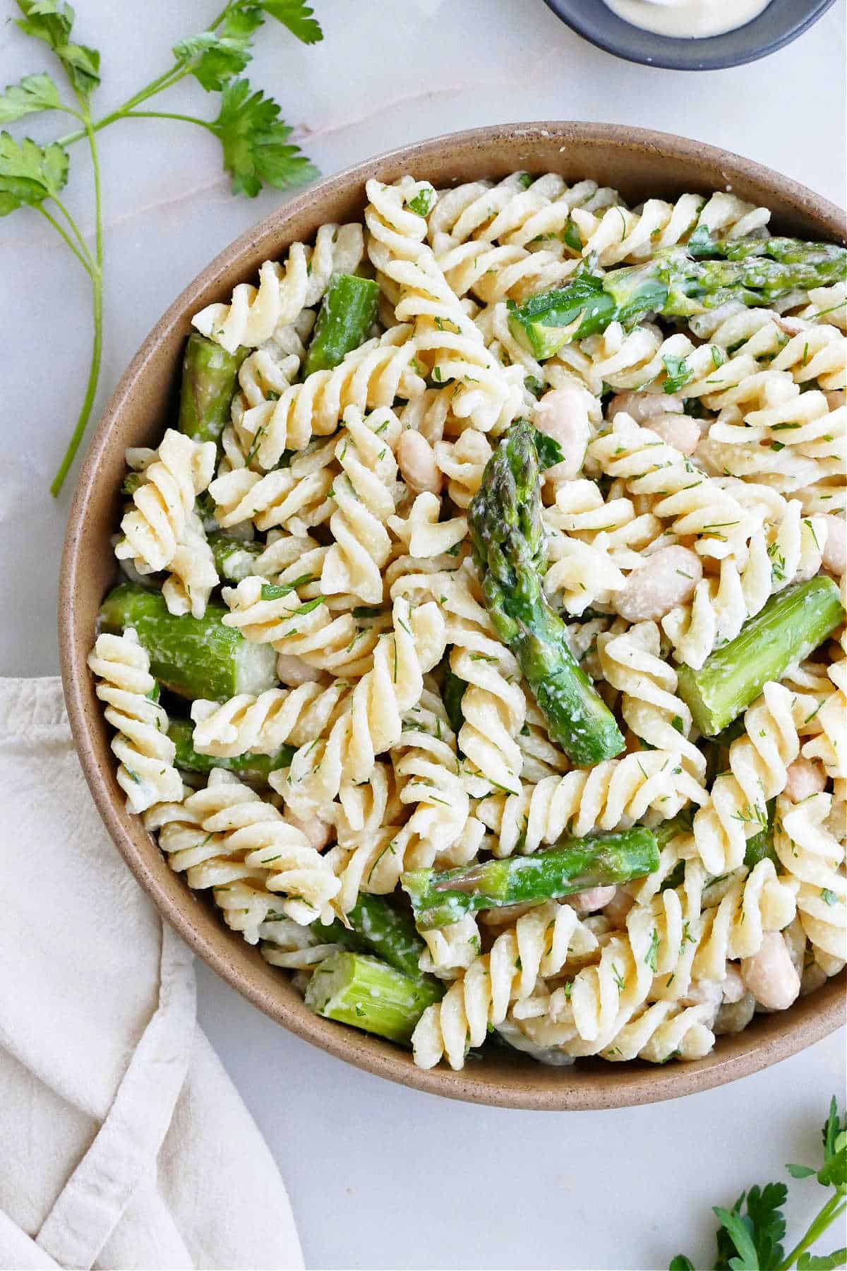 close-up image of pasta salad with asparagus and fresh herbs in a serving bowl