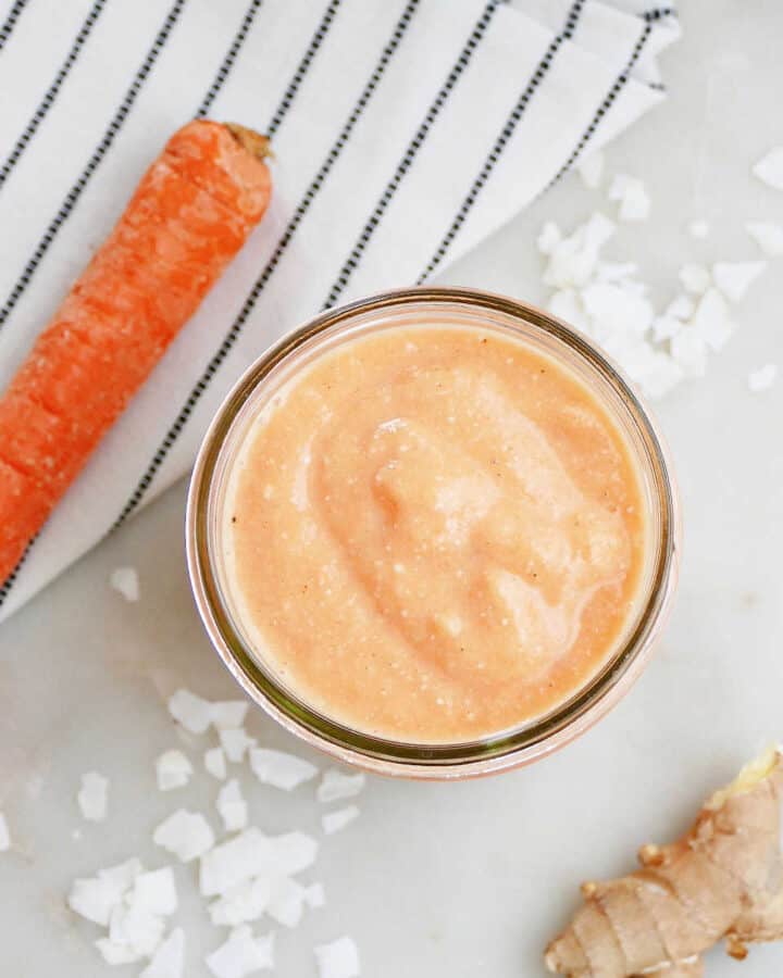 square image of carrot banana smoothie in a glass next to ingredients