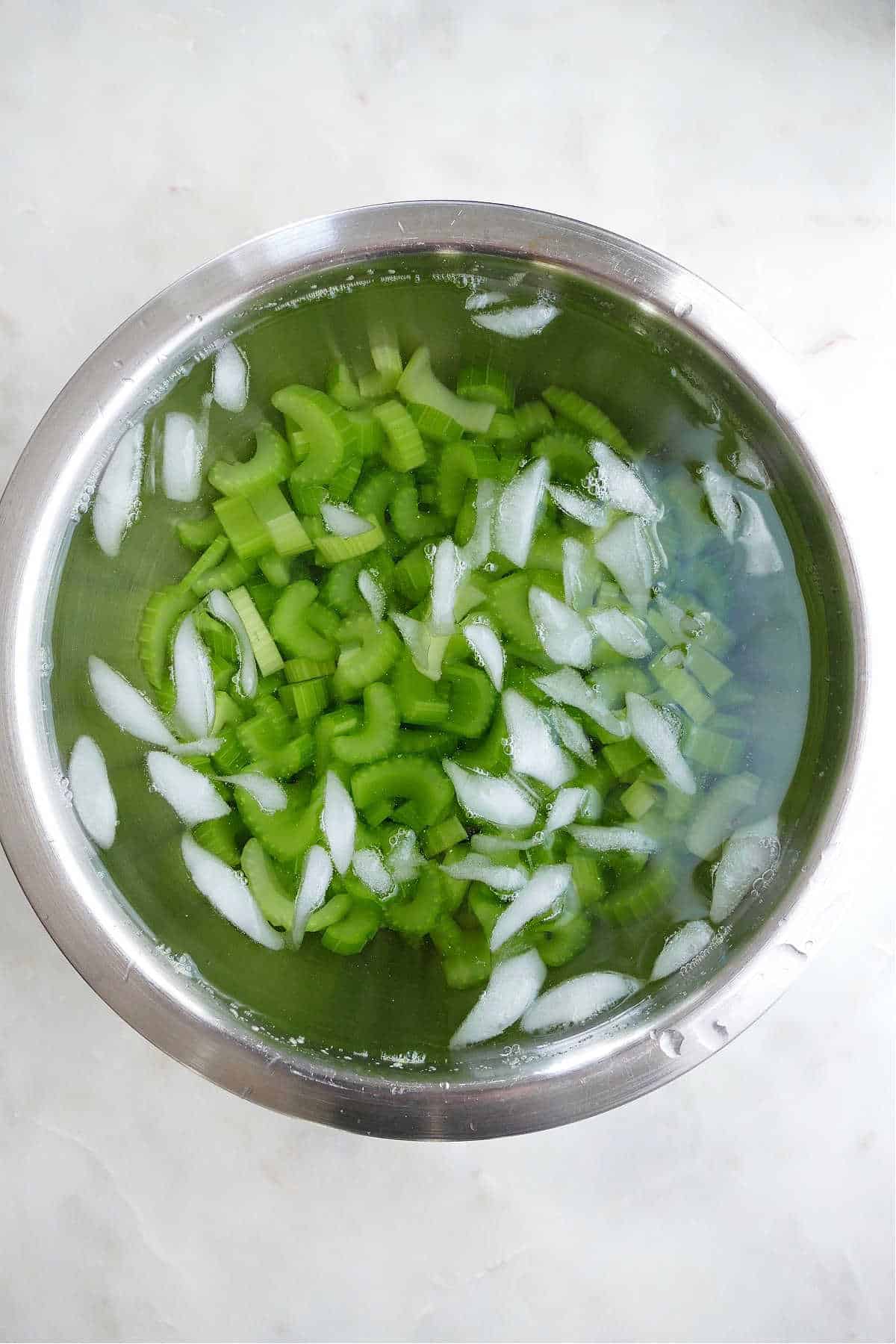 blanched celery in a mixing bowl with ice water