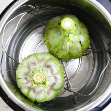 two artichokes upside down in an instant pot before cooking