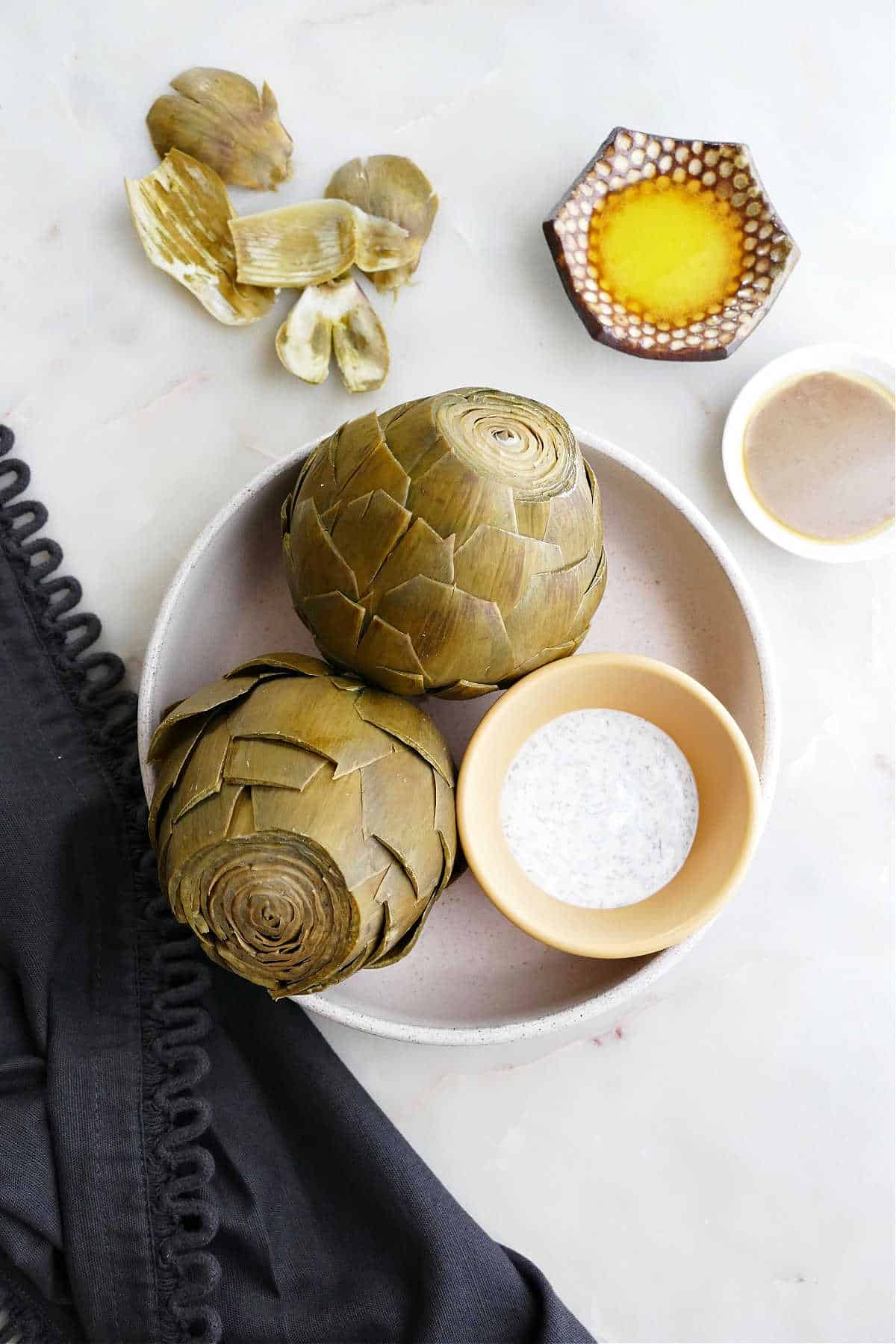 instant pot artichokes in a serving bowl next to dipping sauces