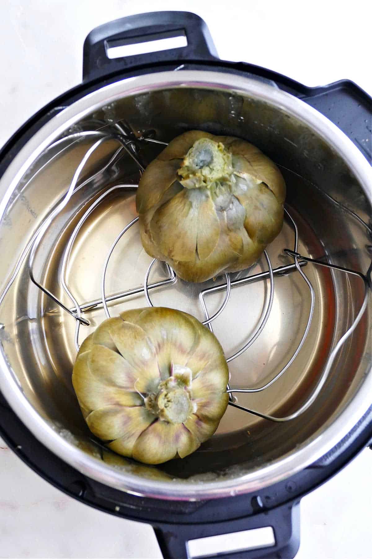 upside down cooked artichokes sitting in an instant pot