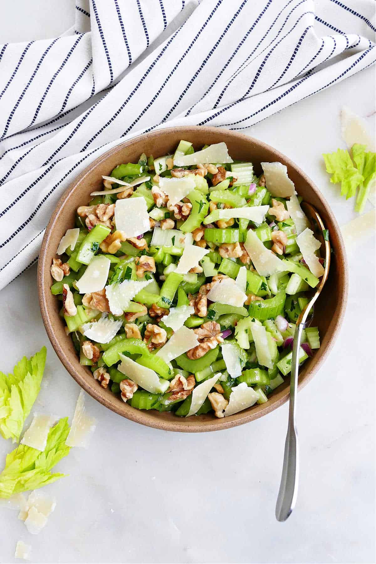 marinated celery salad with shaved parmesan in a serving bowl on a counter