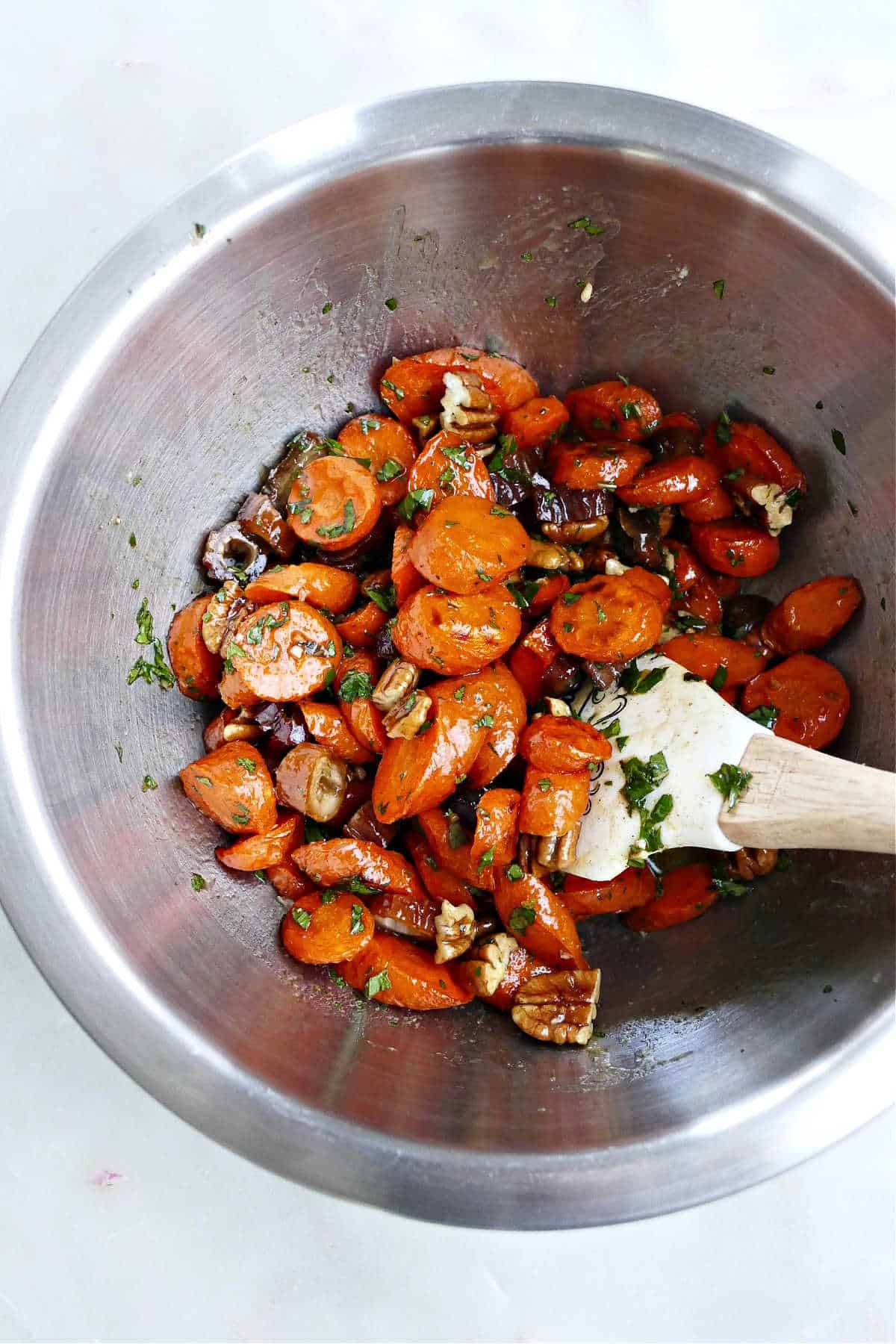 roasted carrots tossed with mint, nuts, and dates in a mixing bowl