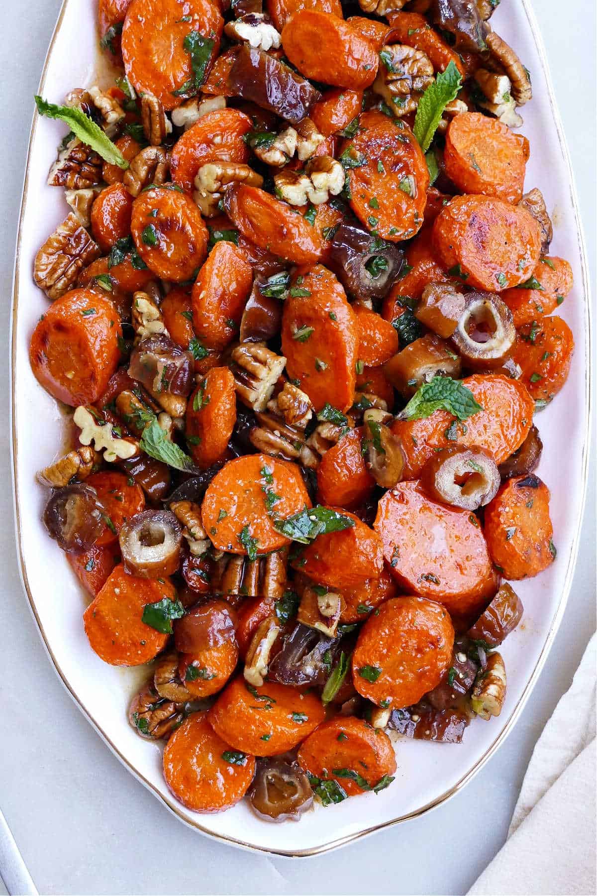 spiced carrots and dates on an oval serving dish on a counter