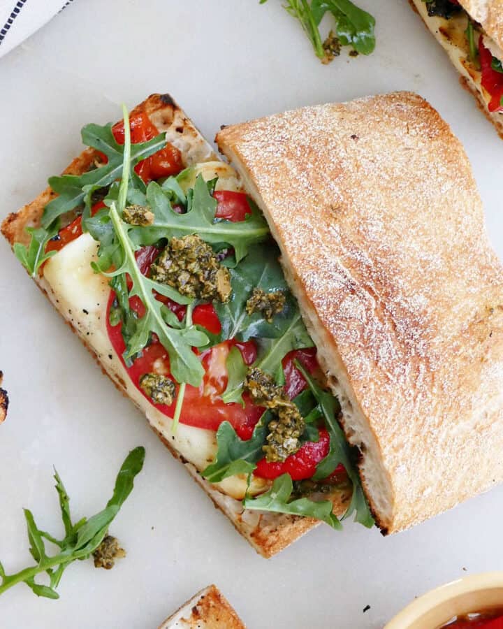 halloumi sandwich on ciabatta bread with veggies on a counter
