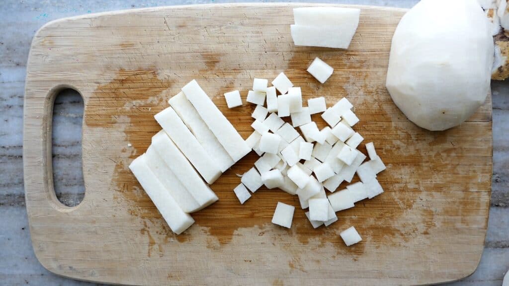 jicama matchsticks and cubes next to each other on a cutting board