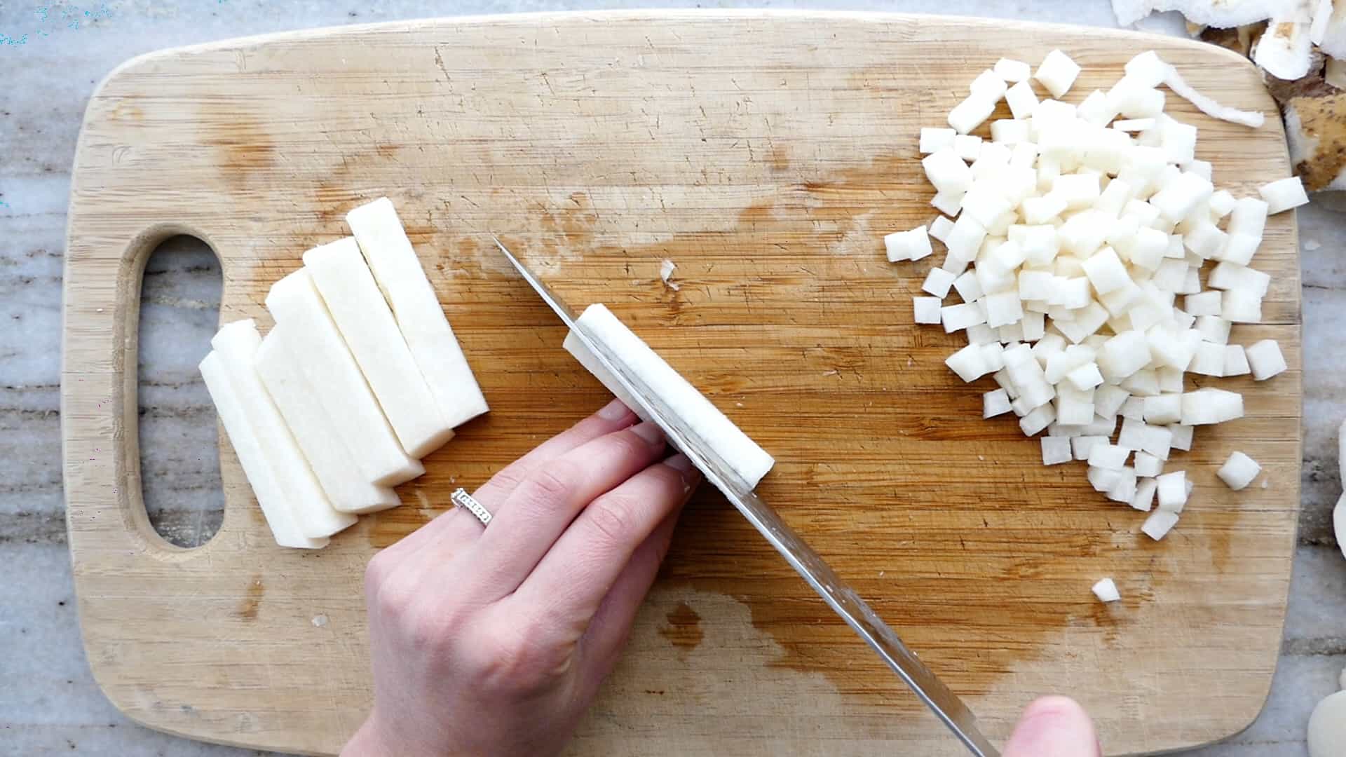 woman cutting thin matchsticks of jicama over a cutting board