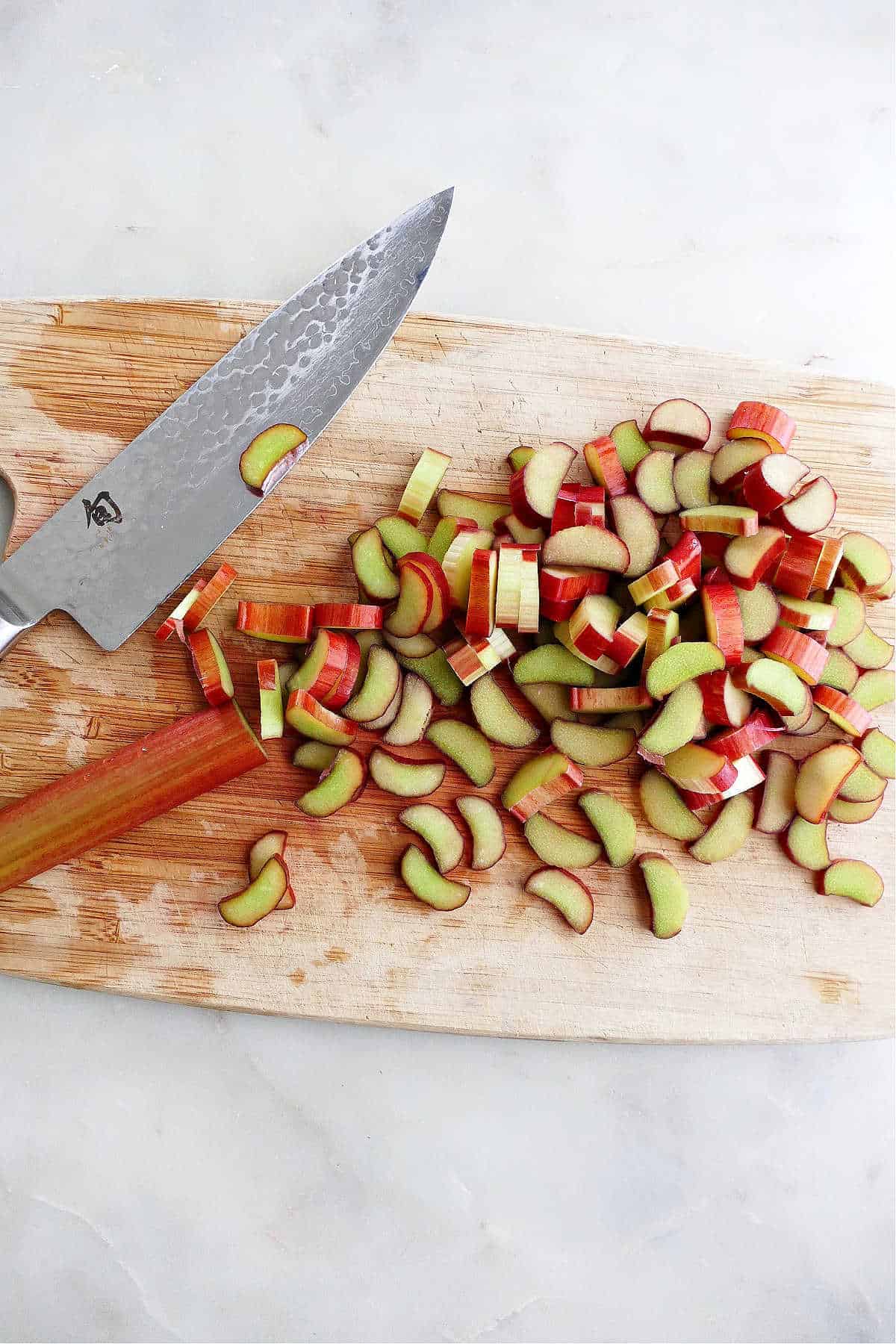 diced rhubarb on a bamboo cutting board next to a chef's knife
