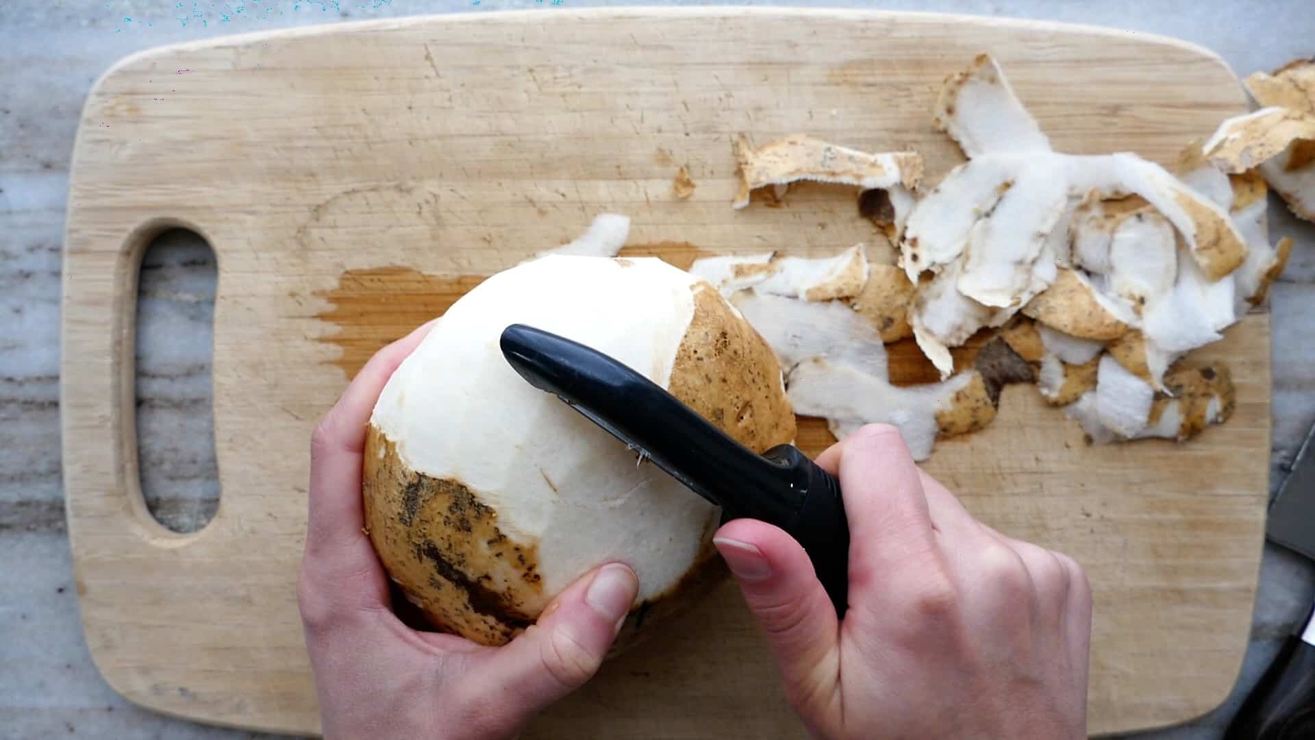 woman peeling jicama with a swivel peeler