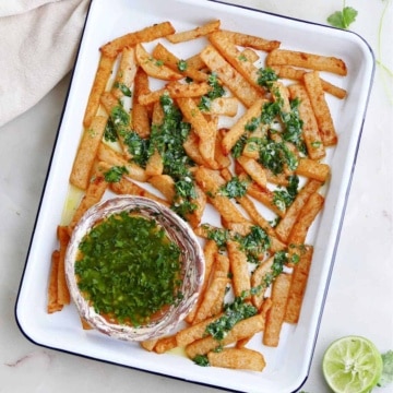 jicama fries drizzled with cilantro lime dressing on a serving tray on a counter