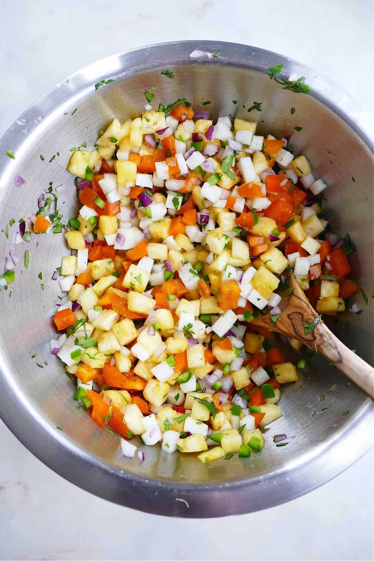 jicama salsa mixed together in a large bowl with a wooden spoon