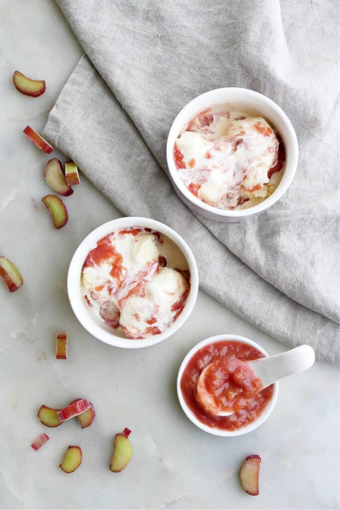 small bowls of vanilla ice cream topped with rhubarb sauce spread out on a counter