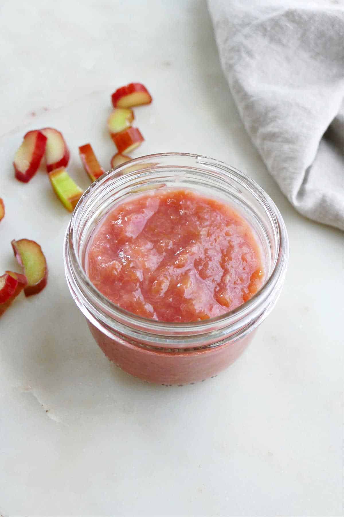 rhubarb sauce in a glass jar next to diced rhubarb and a napkin