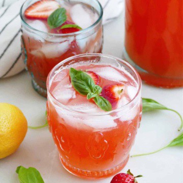 strawberry basil lemonade in front of another glass and pitcher on a counter