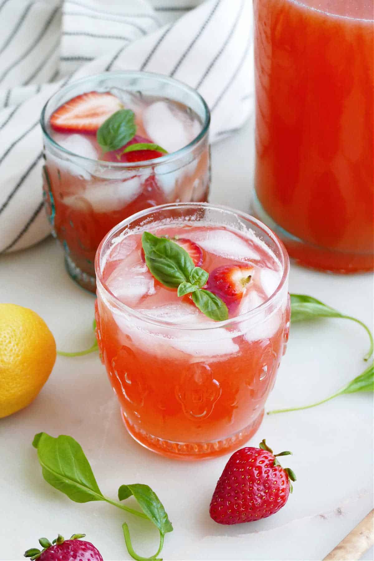 strawberry basil lemonade in front of another glass and pitcher on a counter