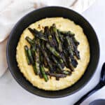 blackened green beans sitting on top of cheesy grits in a serving bowl