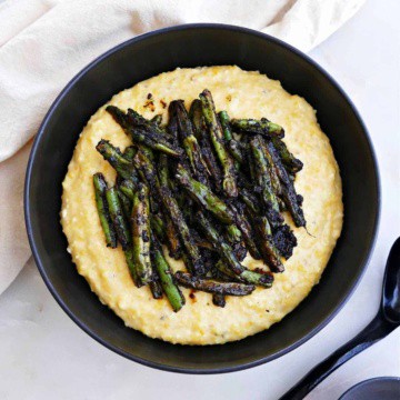 blackened green beans sitting on top of cheesy grits in a serving bowl