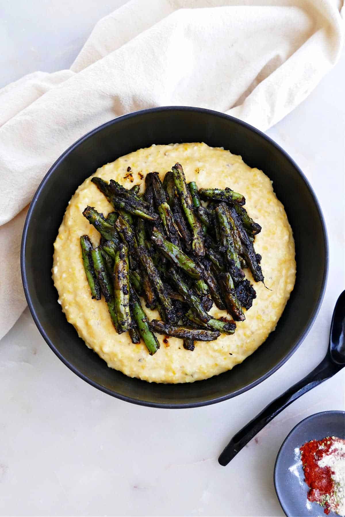 blackened green beans sitting on top of cheesy grits in a serving bowl