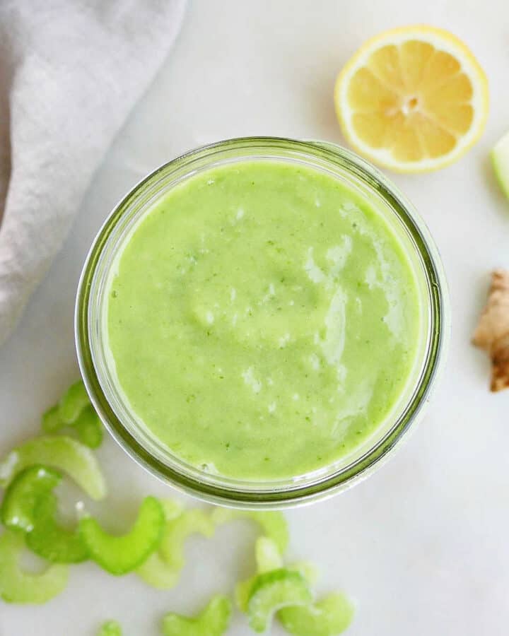 green celery apple smoothie in a glass jar on a counter next to ingredients