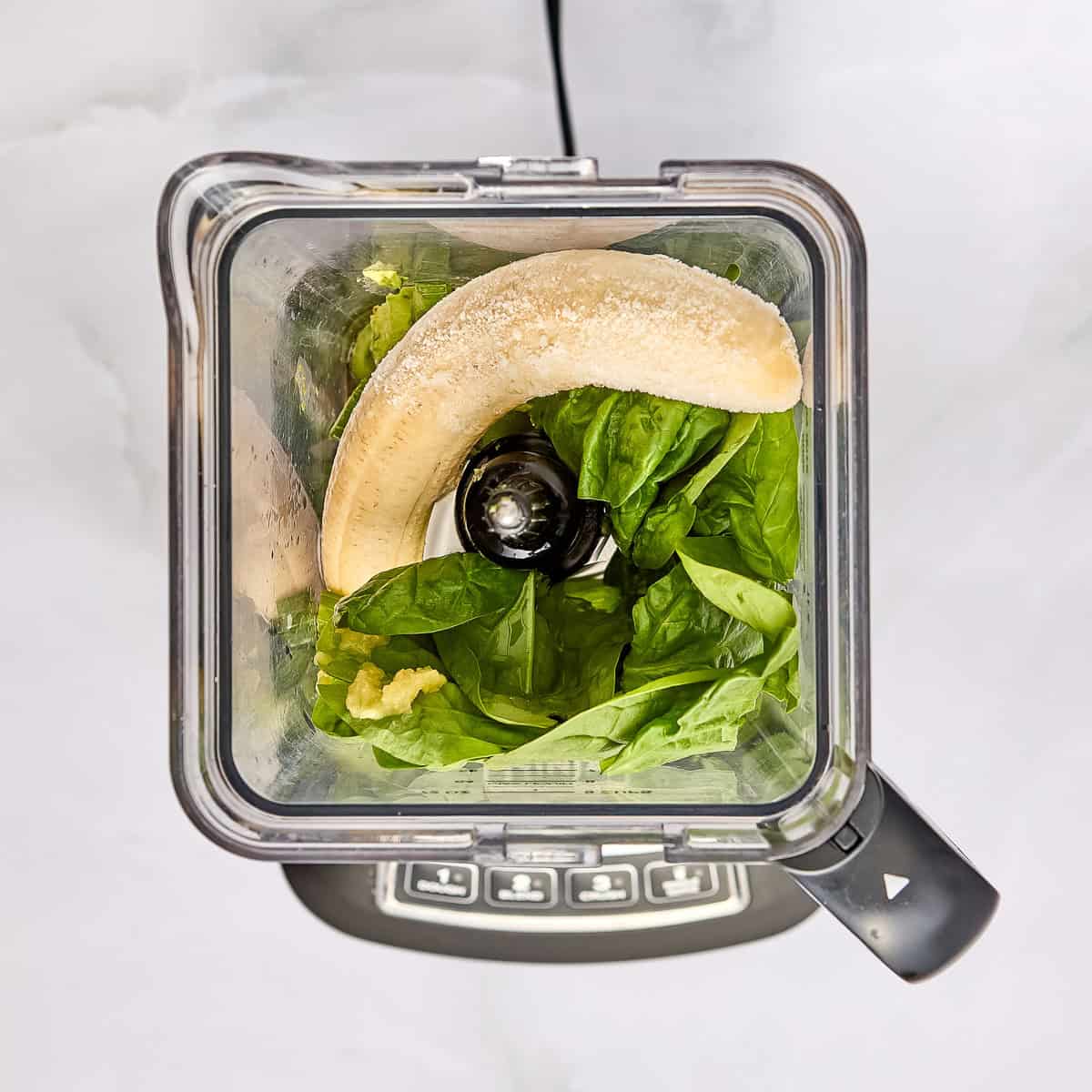 Celery, spinach, banana, avocado, ginger, lemon, apple, and vanilla in a blender.