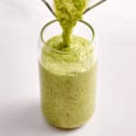 Green smoothie being poured into a glass.