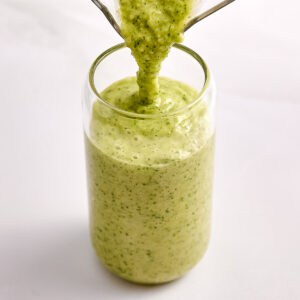 Green smoothie being poured into a glass.