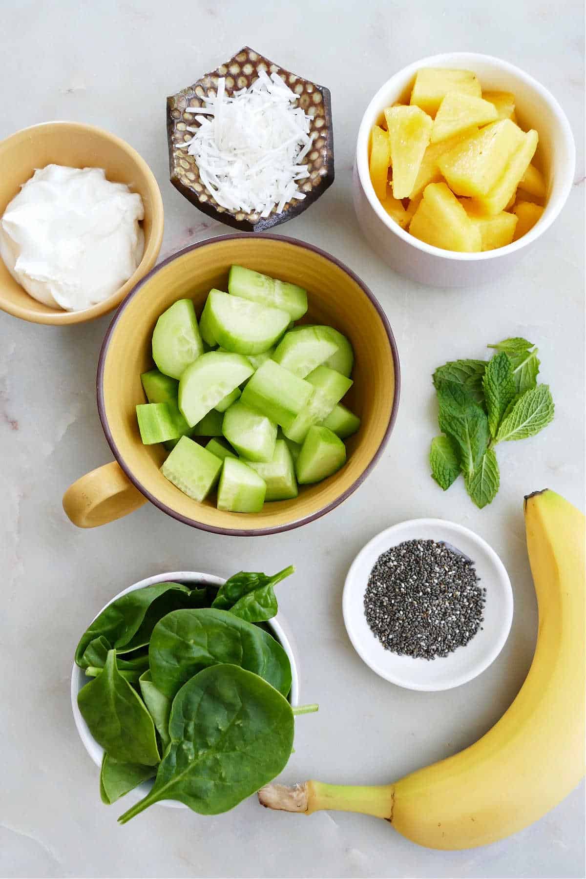 ingredients for a cucumber green smoothie spread out next to each other on a counter