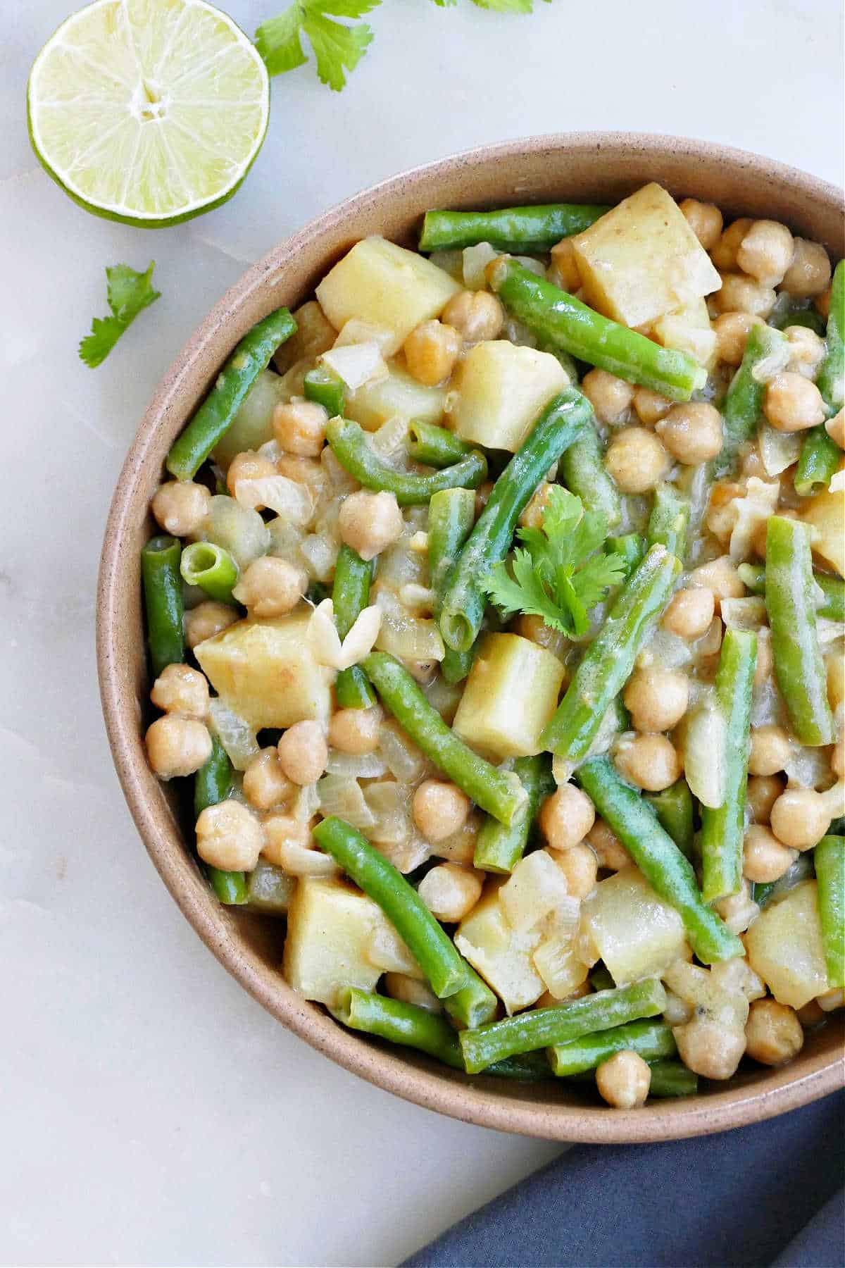green bean and potato curry in a serving bowl topped with cilantro
