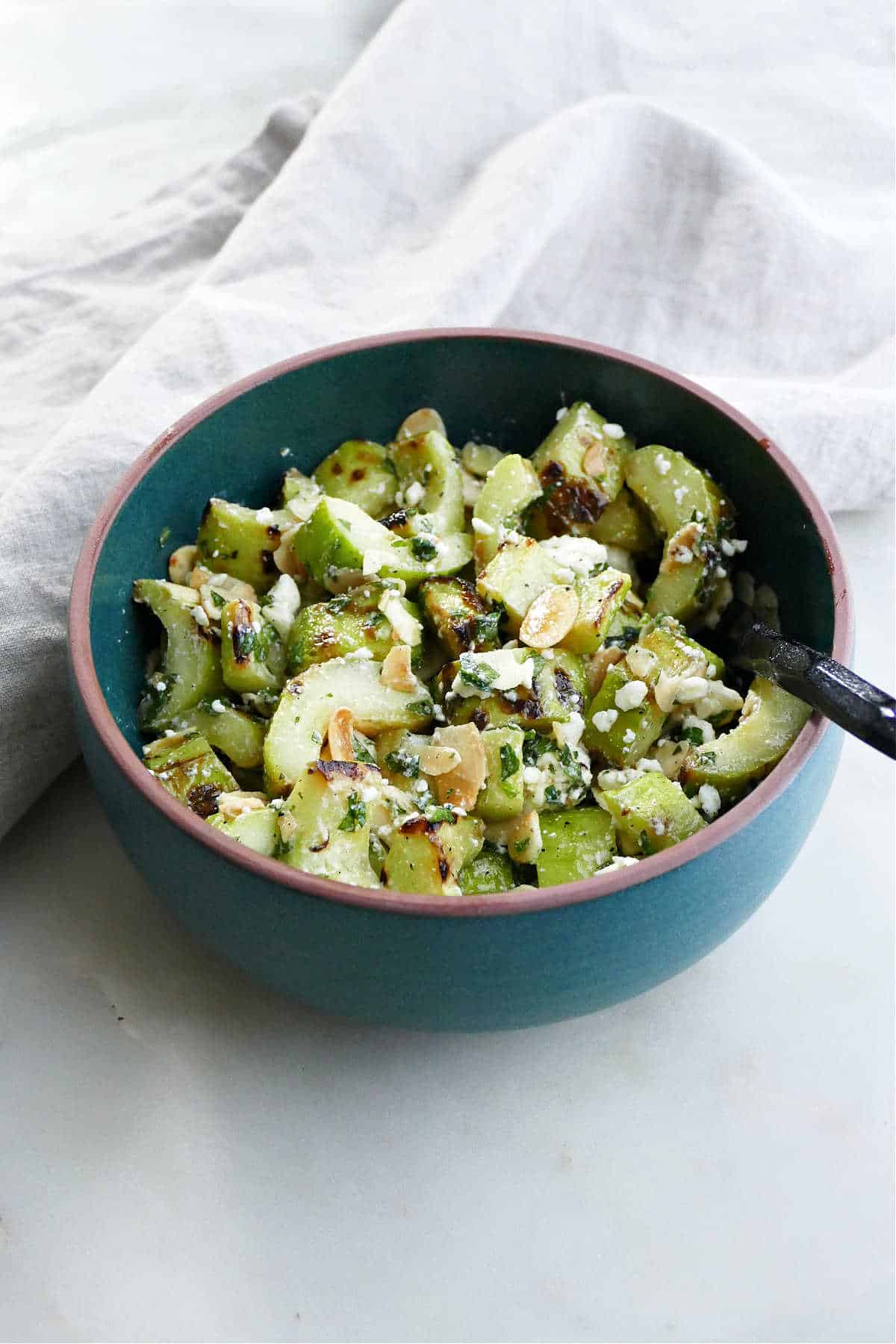 grilled cucumber salad with feta, mint, and almonds in a serving bowl