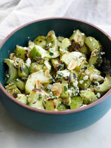 grilled cucumber salad with feta, mint, and almonds in a serving bowl