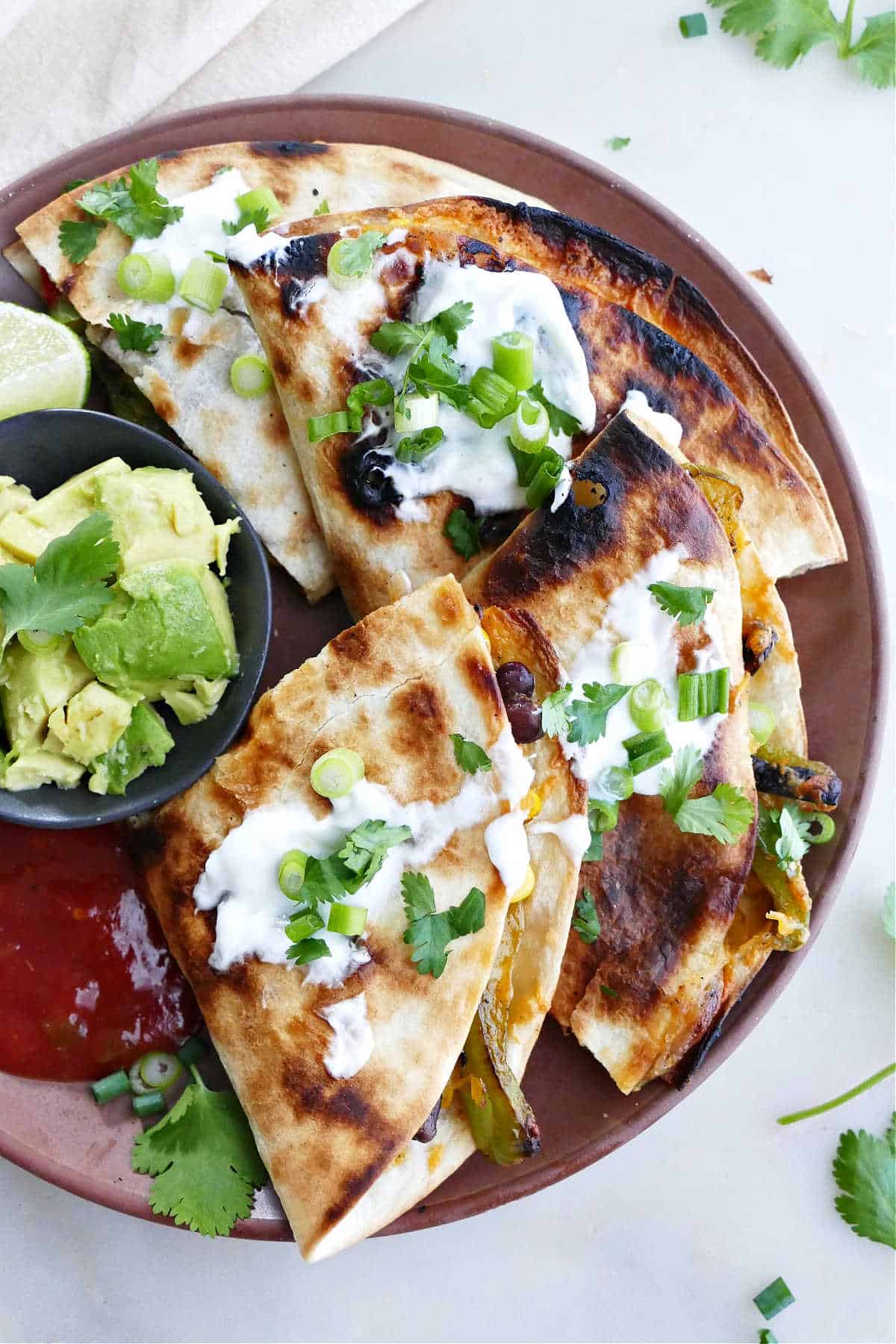 grilled quesadilla sliced into pieces on a serving plate topped with cilantro