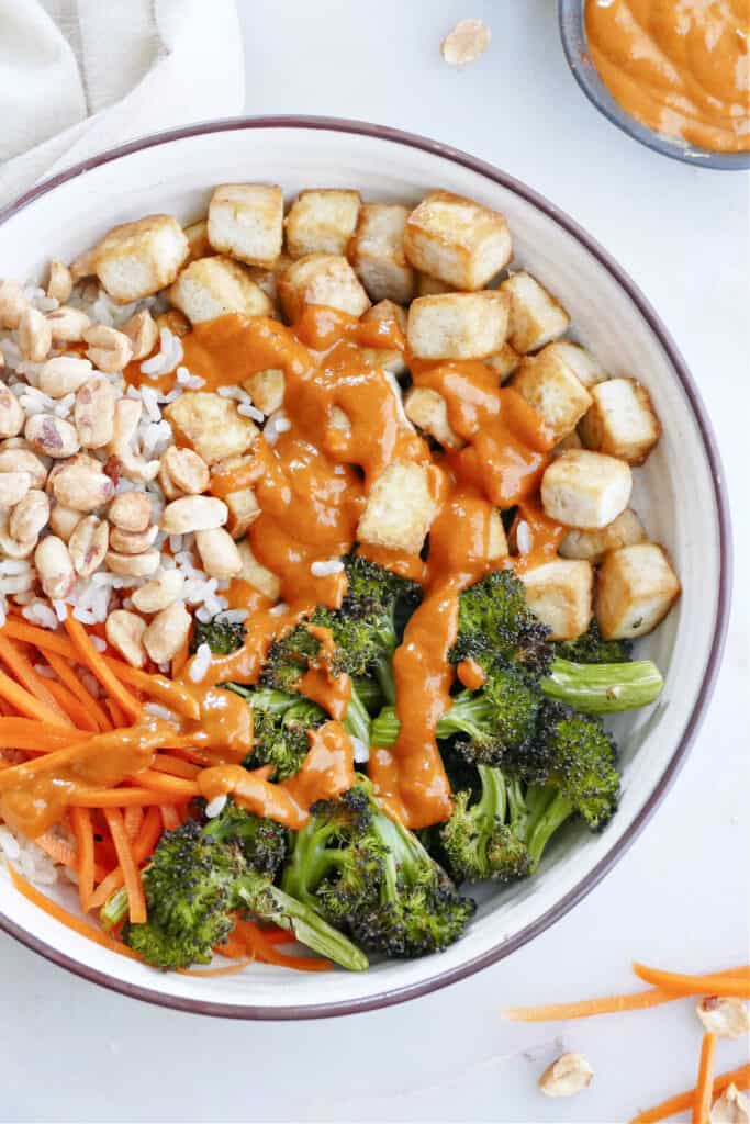 tofu buddha bowl with peanut sauce, rice, and veggies on a counter