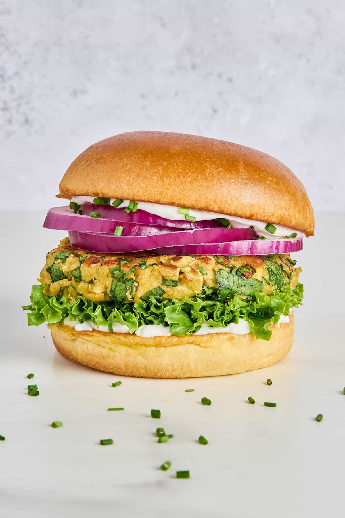 Spinach feta salmon burger with lettuce, yogurt, and onion on a bun.