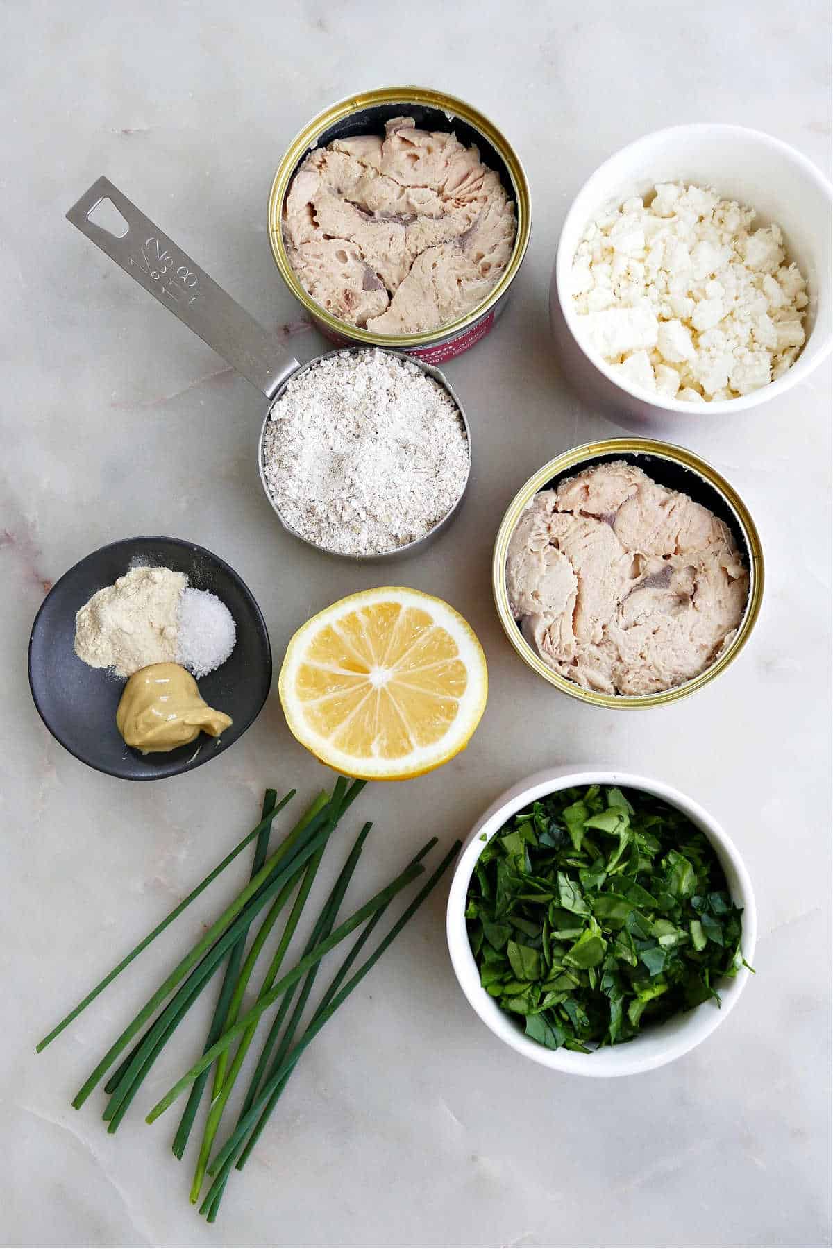 canned salmon, feta cheese, ground oats, lemon, seasonings, and spinach on a counter