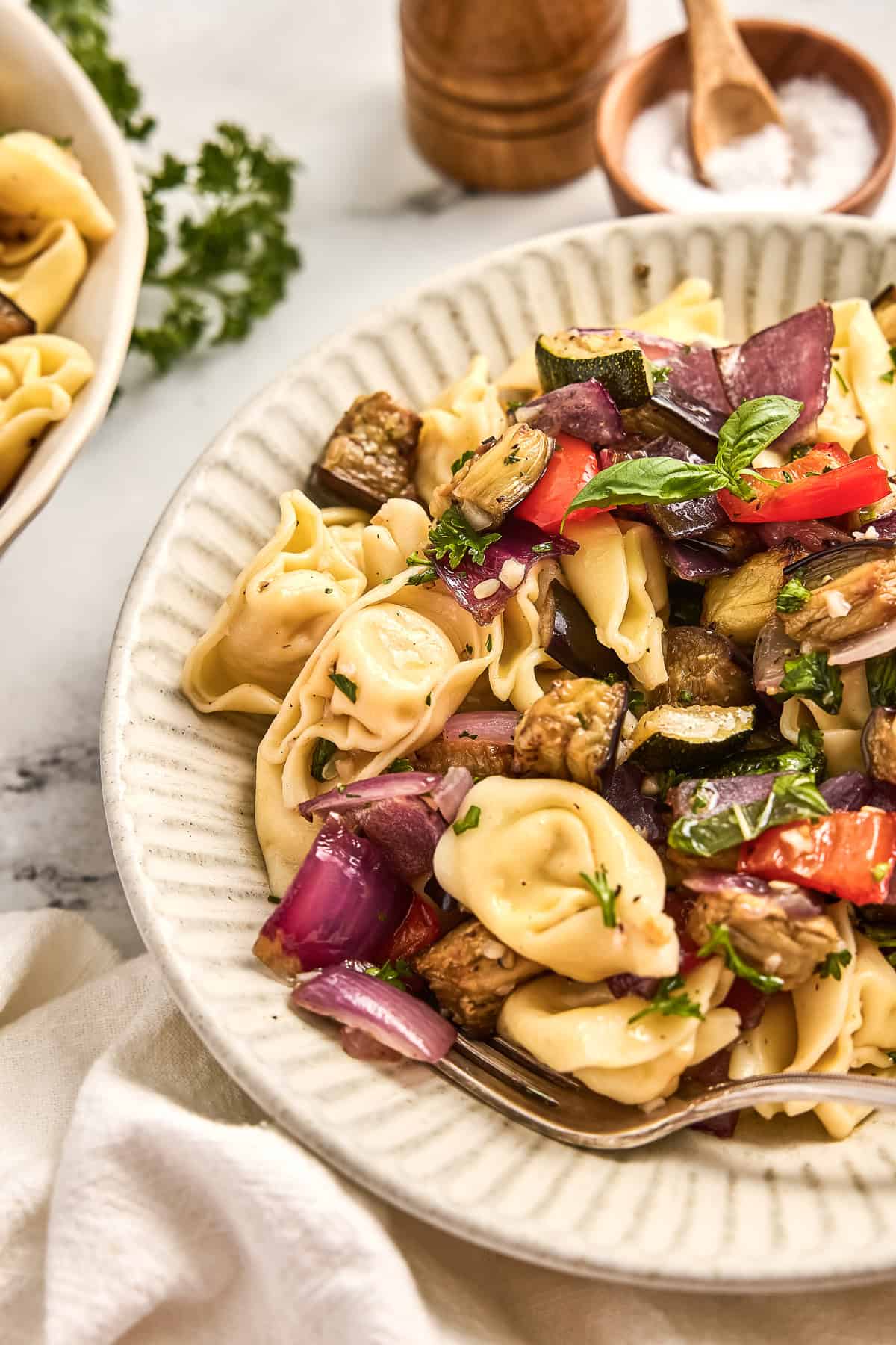 Tortellini salad with roasted vegetables and olive oil herb dressing on a plate.