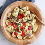 summer tortellini salad in a serving bowl next to napkin on a counter