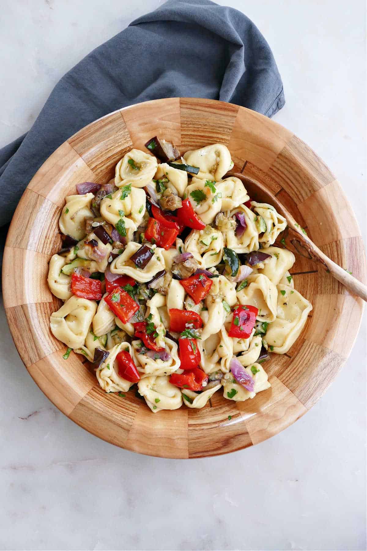 summer tortellini salad in a serving bowl next to napkin on a counter