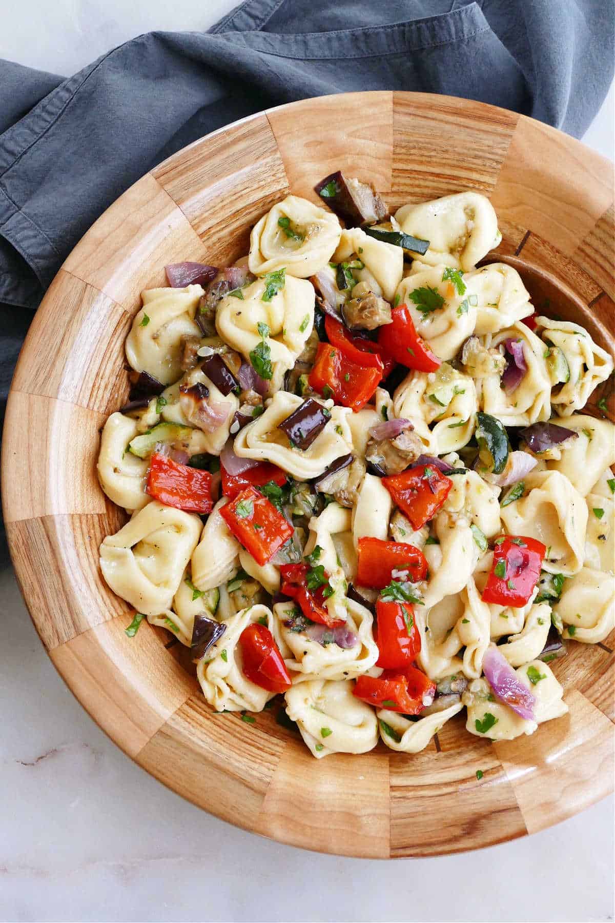 summer tortellini salad in a serving bowl with a spoon on a counter