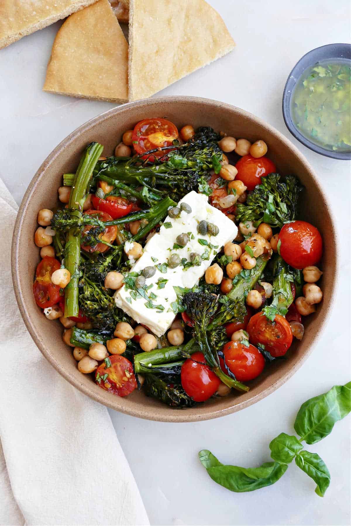 baked feta with vegetables and chickpeas in a serving bowl on a counter