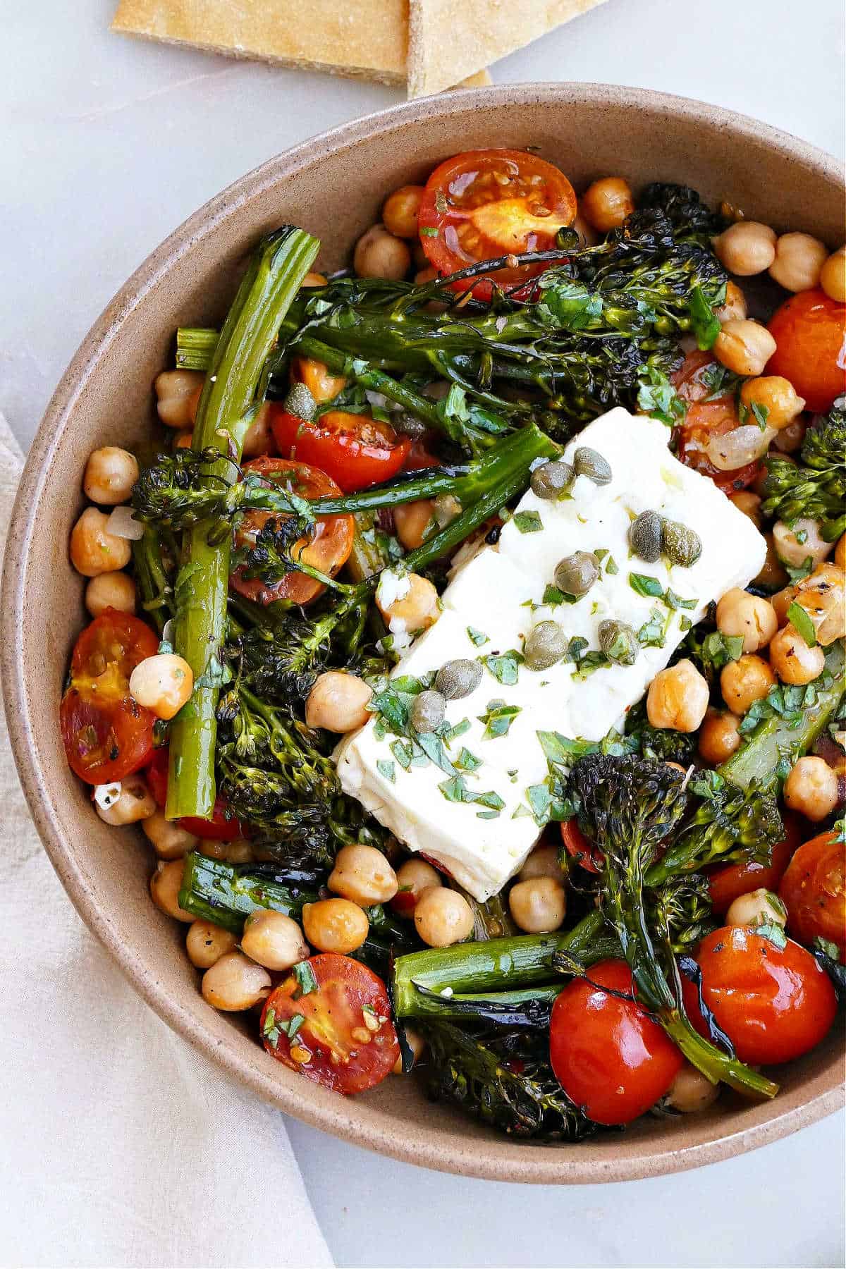 baked feta with vegetables and chickpeas in a serving bowl on a counter