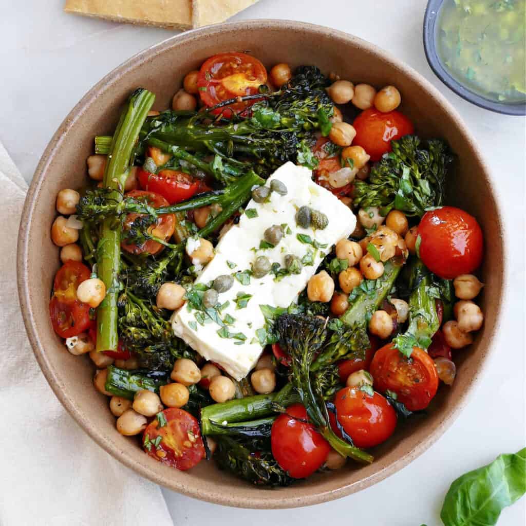 baked feta with vegetables and chickpeas in a serving bowl on a counter