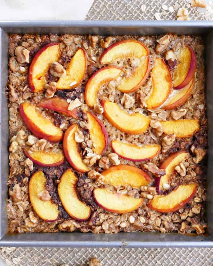 baked peach oatmeal in a square baking dish on a placemat next to a napkin