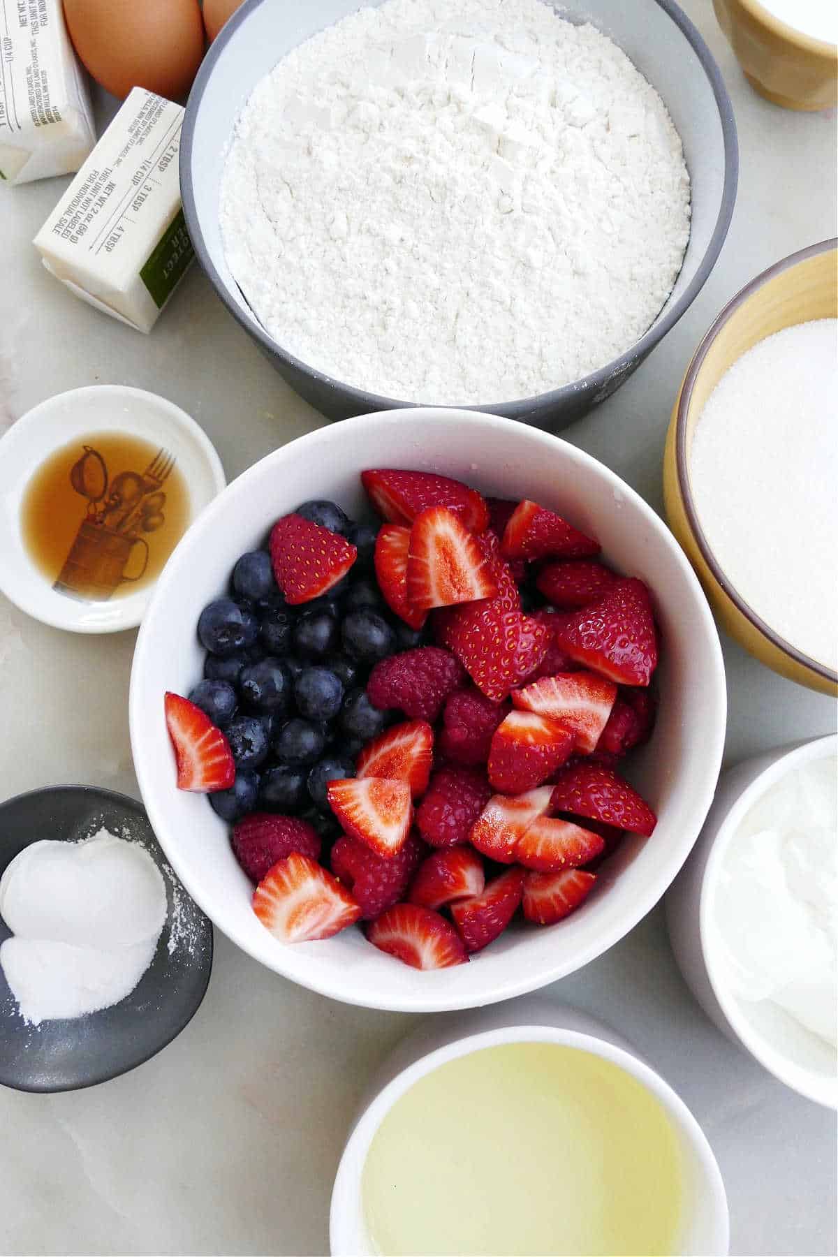 ingredients for berry cupcakes spread out next to each other on a counter